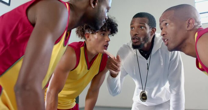 African American coach instructs young biracial and African American athletes
