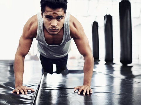 Male person, pushups and training for fitness, sport and health for being a boxer on mat for muscles. Man, wellness and exercise for workout, athlete and cardio strength for commitment in boxing gym