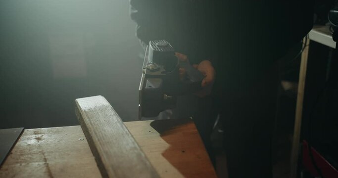 Clumsy woodworker trying to fix his misaligned planer by slamming it on the table in his workshop