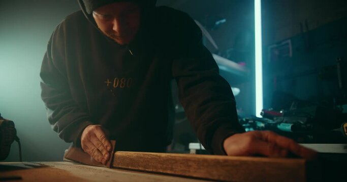Hobby woodworker sanding down the surface of a wooden plank to get it ready for painting
