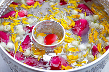 Water with jasmine flower, marigold petal and rose petal in silver bowl. Thai tradition, Songkran...