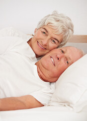 Senior couple, portrait and together in bed, relaxing and love in retirement for bonding on weekend. Elderly people, bedroom and resting or happy in marriage, romance and morning routine at home