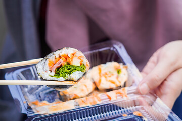 Indonesian street food sushi, illustration of hand holding sushi with chopsticks