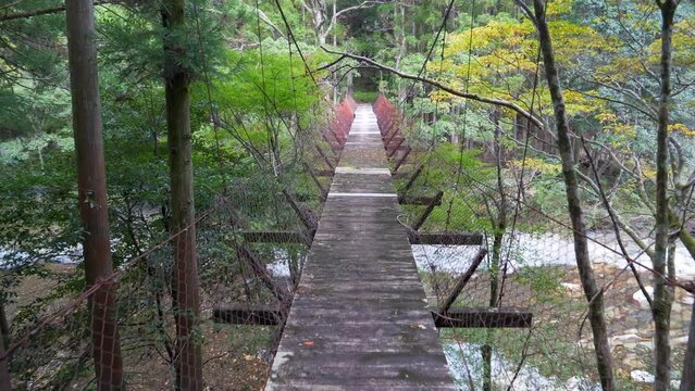 "Wakayama, Japan: Stock footage of a mountainous area features a thrilling journey across a suspension bridge. Experience the scenic beauty as you traverse this breathtaking landscape."