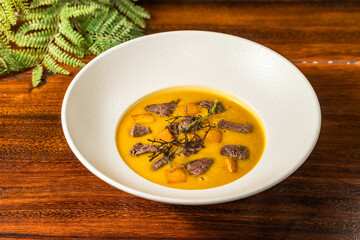 Thick sirloin soup in a hotel restaurant. Meal on wooden table. Delicious soup with spices.