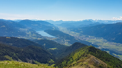 Idyllic hiking trail on alpine meadow with scenic view of lake Millstatt seen from mountain peak Boese Nase in Ankogel Group, Carinthia, Austria. Remote landscape in majestic Austrian Alps in summer