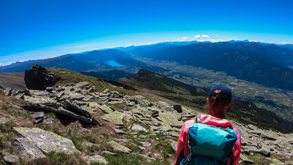 Hiker woman on idyllic hiking trail on alpine meadow with scenic view of lake Millstatt seen from...