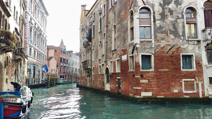 A Venice canal with weathered buildings and moored boats, reflecting the charm and history of the city's unique aquatic urban infrastructure. - obrazy, fototapety, plakaty