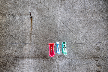 Three.  Three pegs hanging from a line and a nail in a concrete wall.