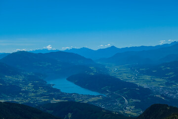 Idyllic hiking trail on alpine meadow with scenic view of lake Millstatt seen from mountain peak Boese Nase in Ankogel Group, Carinthia, Austria. Remote landscape in majestic Austrian Alps in summer