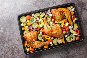 Delicious Mediterranean baked chicken legs with vegetables and feta cheese close-up on a baking...