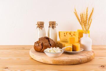 A large round wooden tray with gifts of traditional food for the Jewish holiday of Shavuot. A vase with ears of corn. Front view.