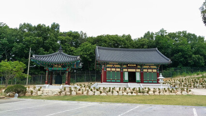 Fototapeta na wymiar A traditional Korean pavilion set against a backdrop of trees and a stone wall.