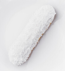 eclair in white glaze and coconut flakes