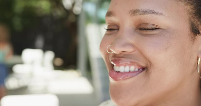 Close-up of a young biracial woman smiling outdoors with copy space