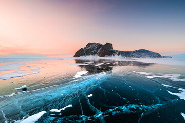 Blue transparent ice on Baikal lake in winter. Sunrise at Khoboy cape of Olkhon island