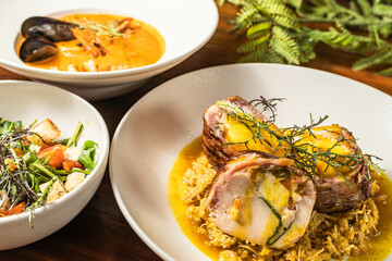 Exquisite medallions on a base of orange rice with salad and seafood soup. Delicious hotel restaurant food.
