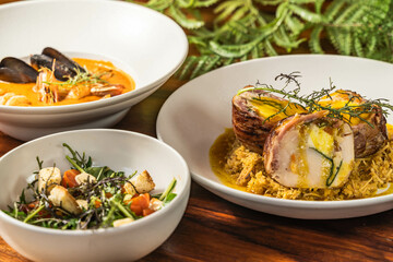Exquisite medallions on a base of orange rice with salad and seafood soup. Delicious hotel restaurant food.