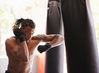 Fitness, punching bag and black man in boxing gym for exercise, challenge or competition training....