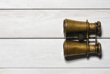 Retro binoculars on the old wooden flat lay desk table background with copy space. Travel...