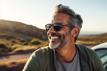 Portrait of a handsome middle-aged man wearing sunglasses and smiling while standing outdoors. - Powered by Adobe