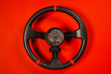 Sport car steering wheel and tachometer on the red top view background close up. Motorsport concept.