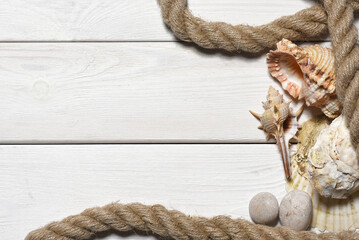 Seashells, mooring rope and pebble stones on the white wooden desk table background top view. Sea...