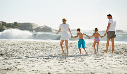 Parents, children and hand holding on beach for travel together at ocean for trip connection, bonding or love. Man, woman and siblings with back view at sea in Florida for vacation, outdoor or family