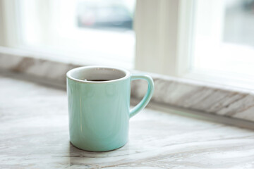 A big blue mug of black coffee on a marble windowsill - 741292820