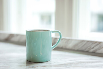 A big blue mug of black coffee on a marble windowsill