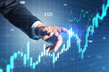 Close up of businessman hand pointing at growing forex chart on blurry background. Financial...