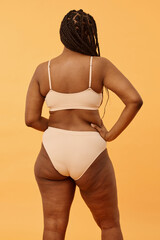 Vertical medium long back view shot of unrecognizable Black woman with curvy body wearing...