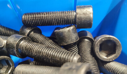 Close-up of metric screws, in burnished steel, in a blue plastic tray.