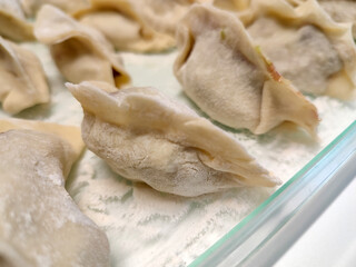 Close-up of a handmade jiaozi (Chinese ravioli) on a floured table.