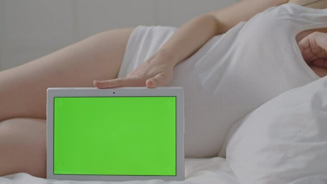 Pregnant Woman hold tablet with green screen for modern interaction, customize for app demonstration and layout insertion in a comfortable environment. Screen Replacement for advertising promotion