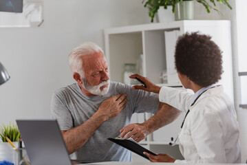 Obraz premium An African-American woman doctor specialist consults with an elderly male patient in her office