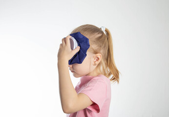 A little girl aged seven holds a cold bag of ice to her head. The concept of applying cold for...