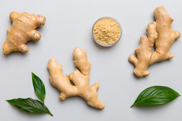 Finely dry Ginger powder in bowl with green leaves isolated on colored background. top view flat lay