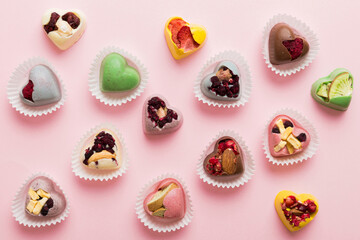 chocolate sweets in the form of a heart with fruits and nuts on a colored background. top view with space for text, holiday concept