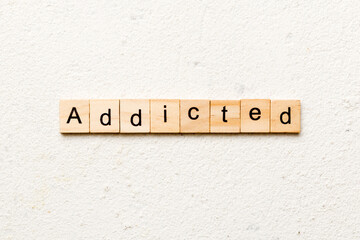 Addicted word written on wood block. Addicted text on cement table for your desing, Top view concept