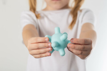 A blonde girl holds a model of a virus in her hands. Concept of ARVI and influenza virus in...