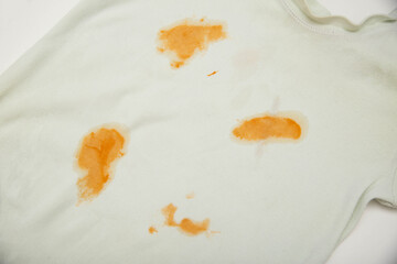 Orange stains on children's clothes from fruit puree. The concept of cleaning stains on clothes...