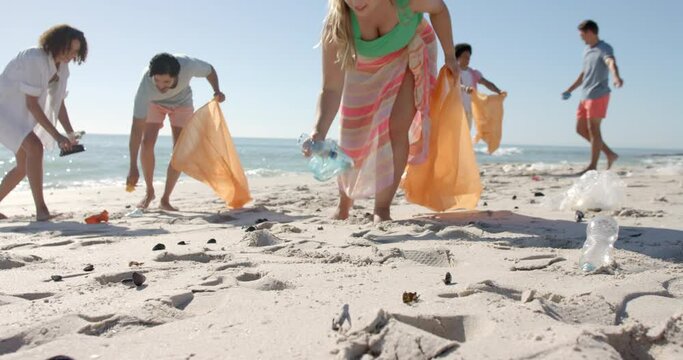 Diverse volunteers clean up a beach, with copy space