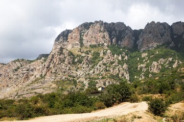 Rocky mountain landscape with winding dirt road under dramatic sky
