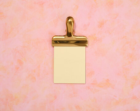 A gold clip and a sheet from a notepad. Flat lay composition.