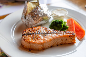 A delectable plate of Norwegian salmon, perfectly grilled with a side of baked potatoes, fresh...