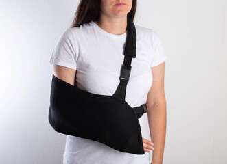 A girl in white with a fixing black bandage on her arm after an injury, a fracture of the radius...