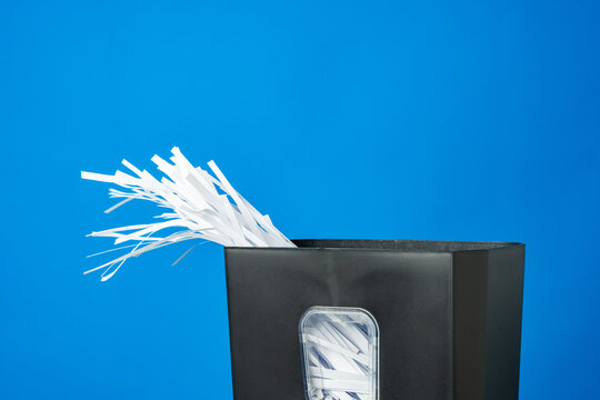 Office paper shredder on blue studio background - Powered by Adobe