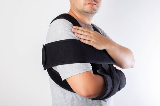 A man in a black bandage supporting the shoulder joint after ligament damage and bruise. Dislocation of the shoulder joint, fracture of the collarbone, close-up