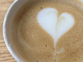Paper mug of latte or Americano coffee with milk, top view. A cup of cappuccino with heart-shaped...